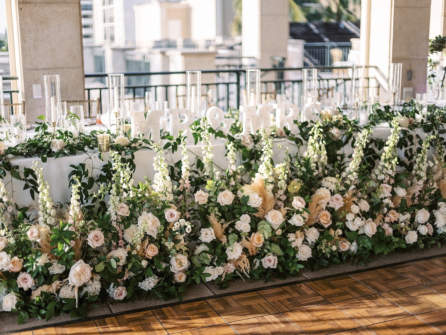 head table at a wedding covered in greenery and flowers