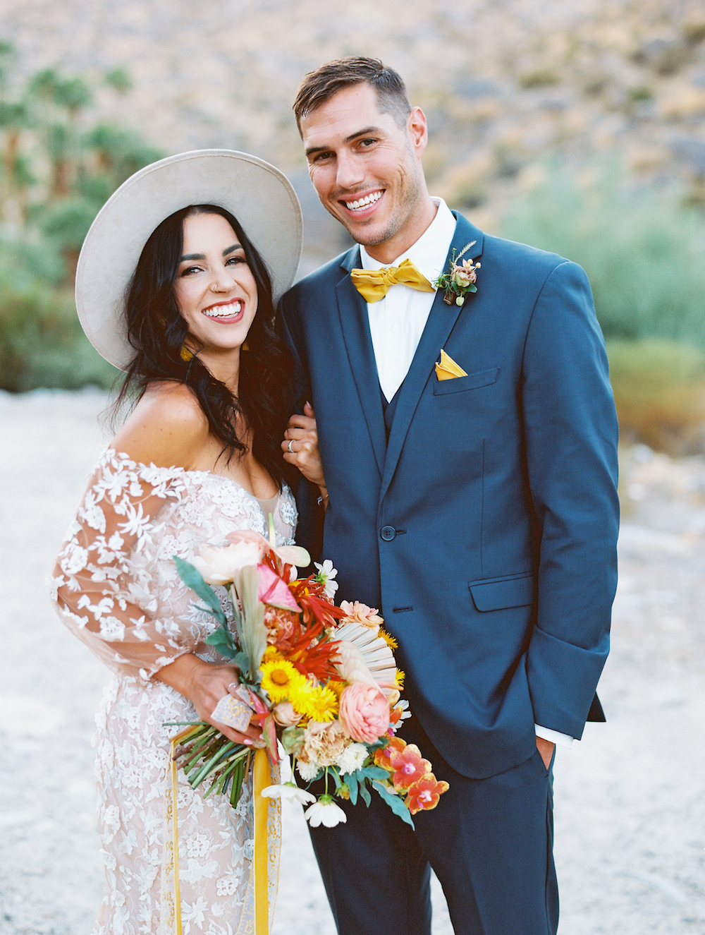 wedding couple bride in hat and groom in navy suit in palm springs