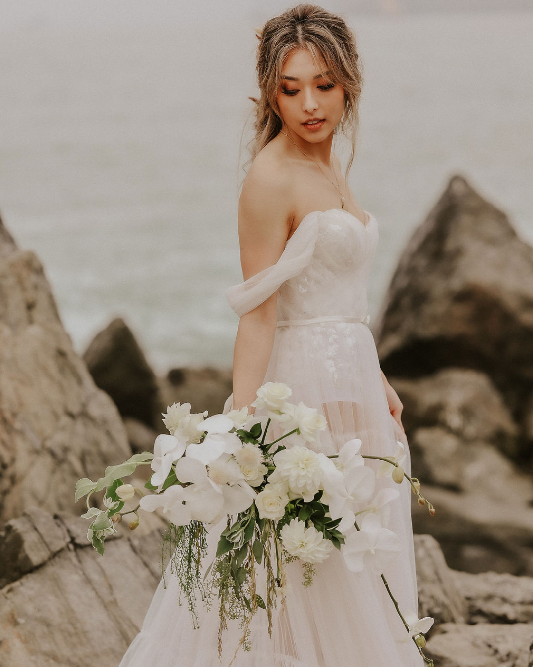 Bride in a an off-the-shoulder wedding dress by the ocean
