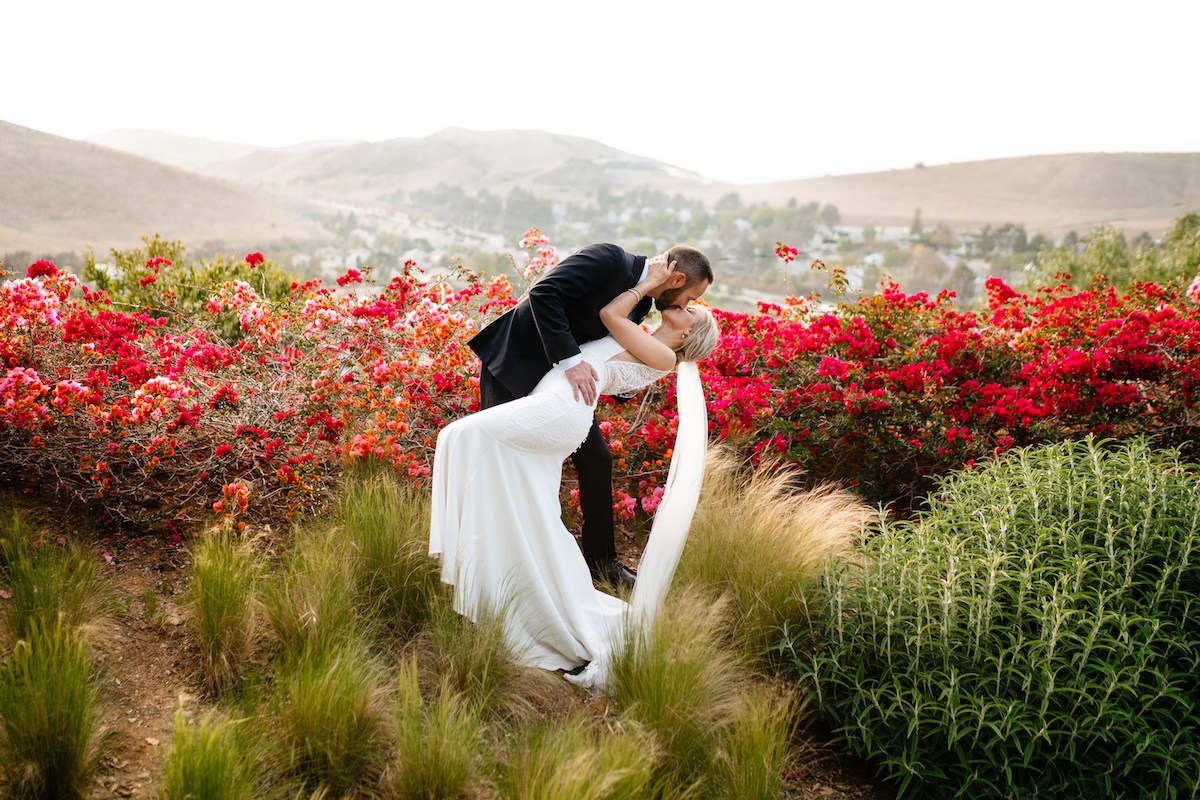 couple kissing by bougainvillea bush in California 