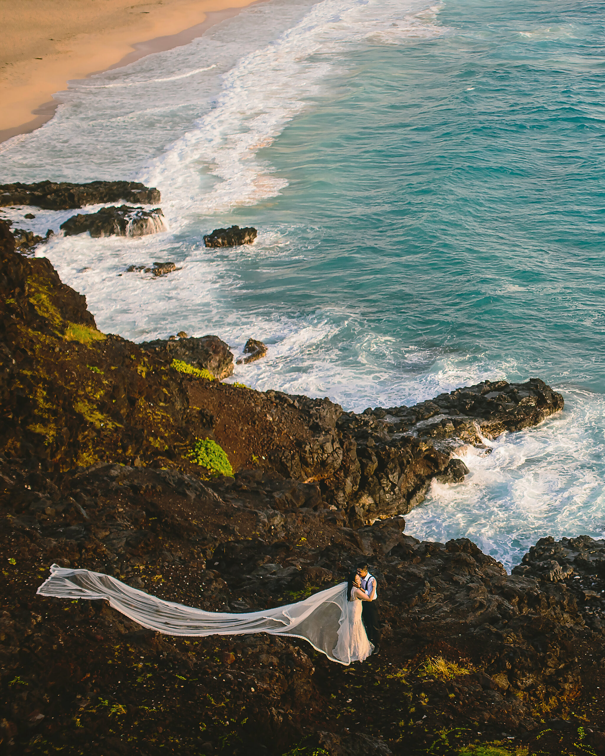 Bride and groom on rocks by beach