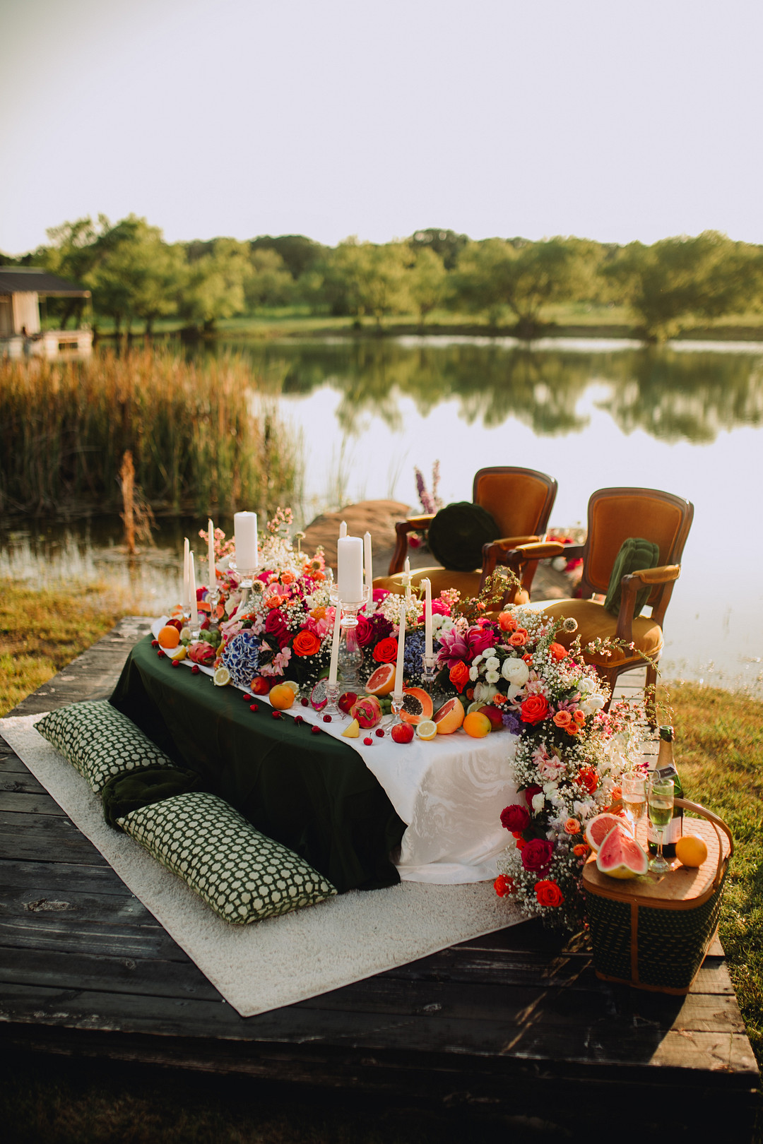 Small sweetheart table with overflow of flows and centerpieces beside a lake