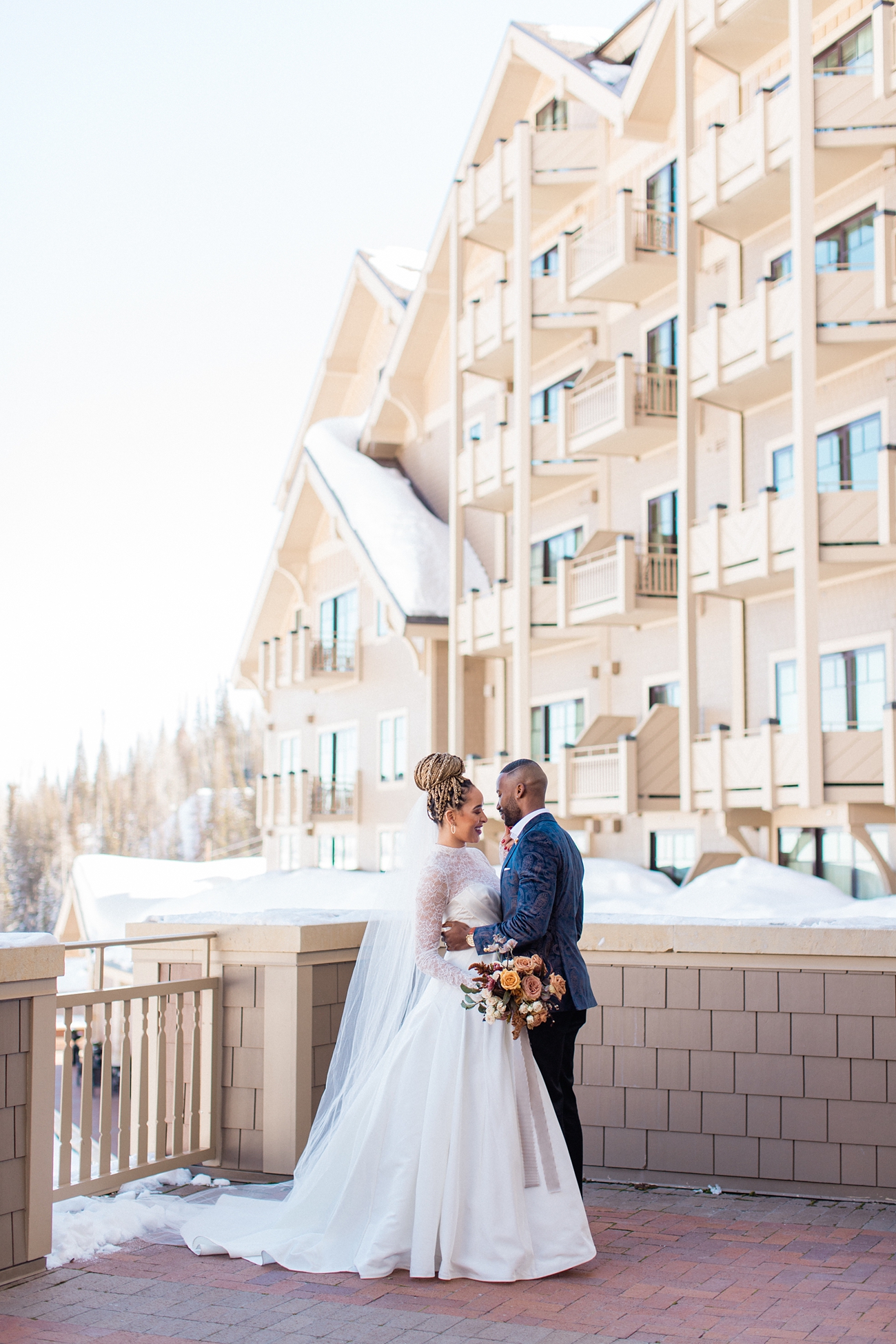 Black wedding couple in front of snowy mountain resort