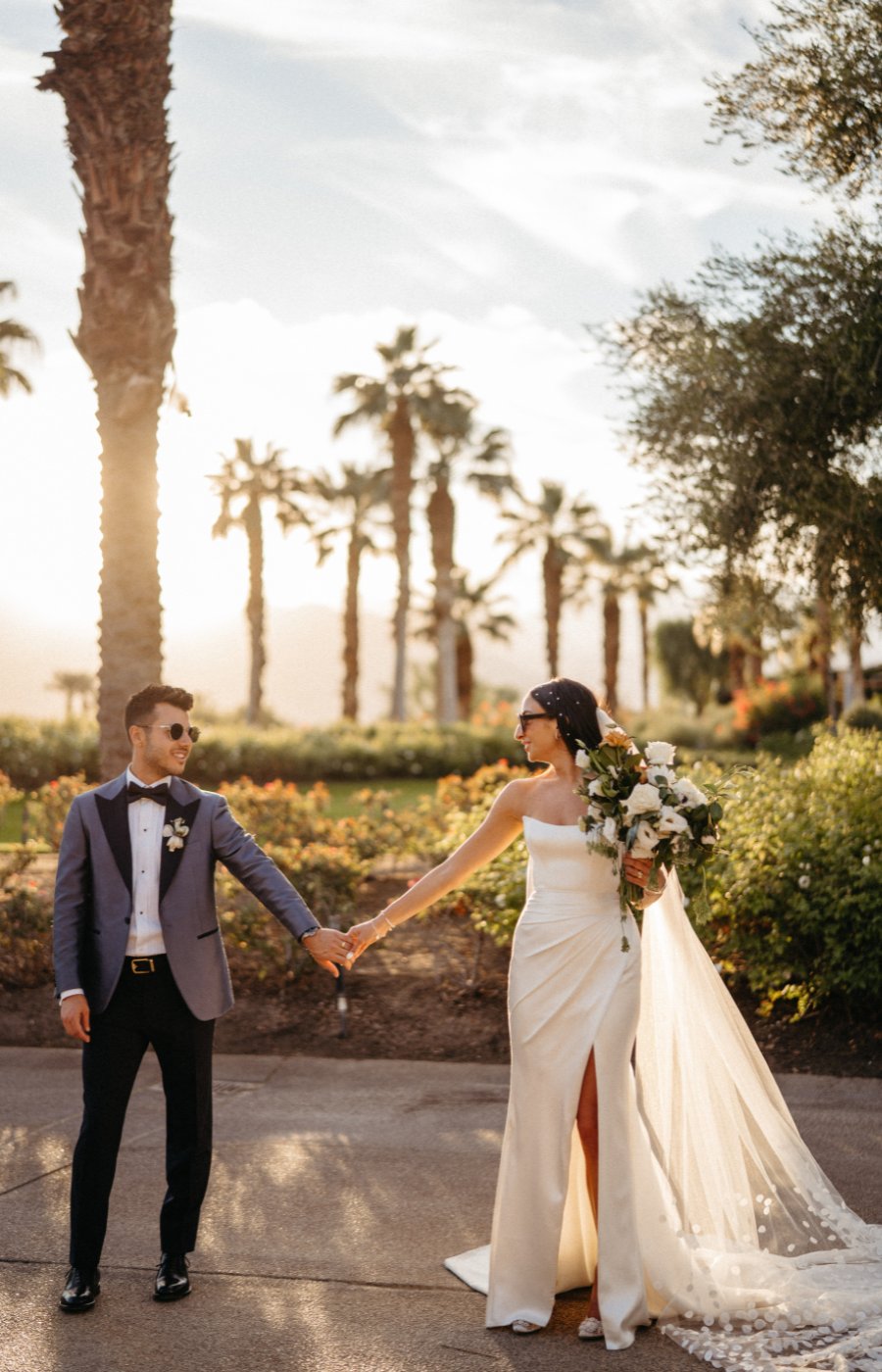 Bride and groom holding hands in Palm Desert during a sunset.