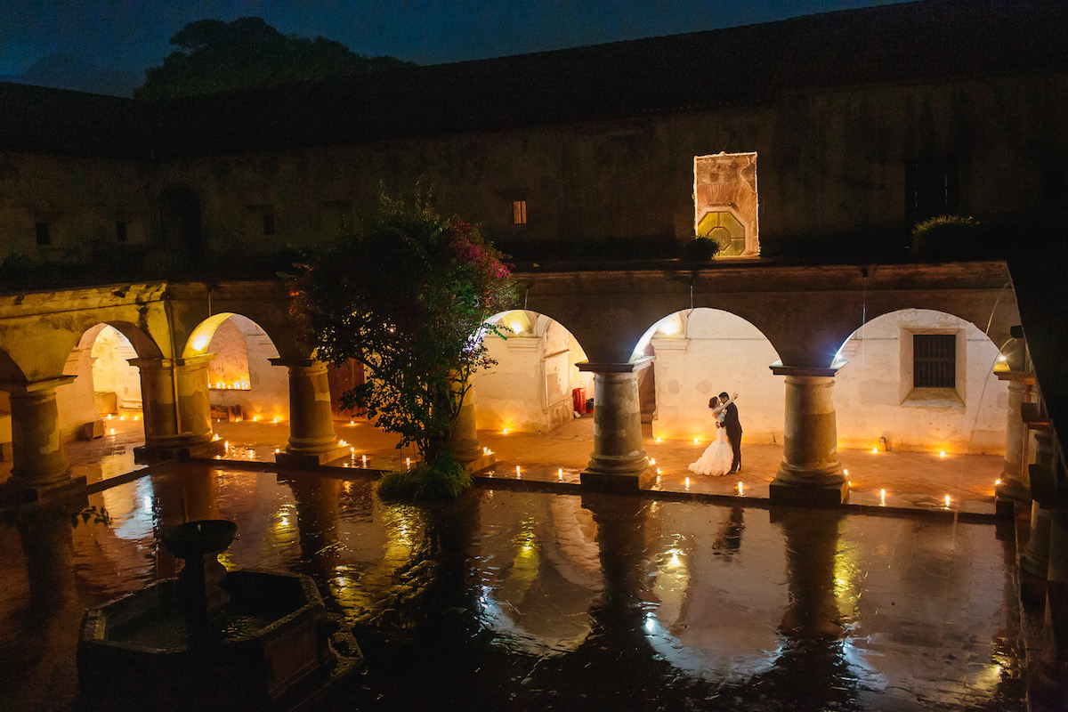 Couple at their destination wedding kissing by a villa and lake