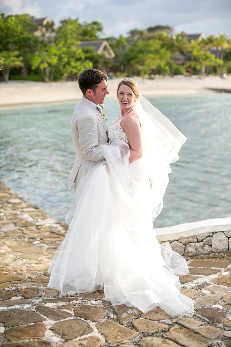 Bride and groom smiling and posing by tropical beach