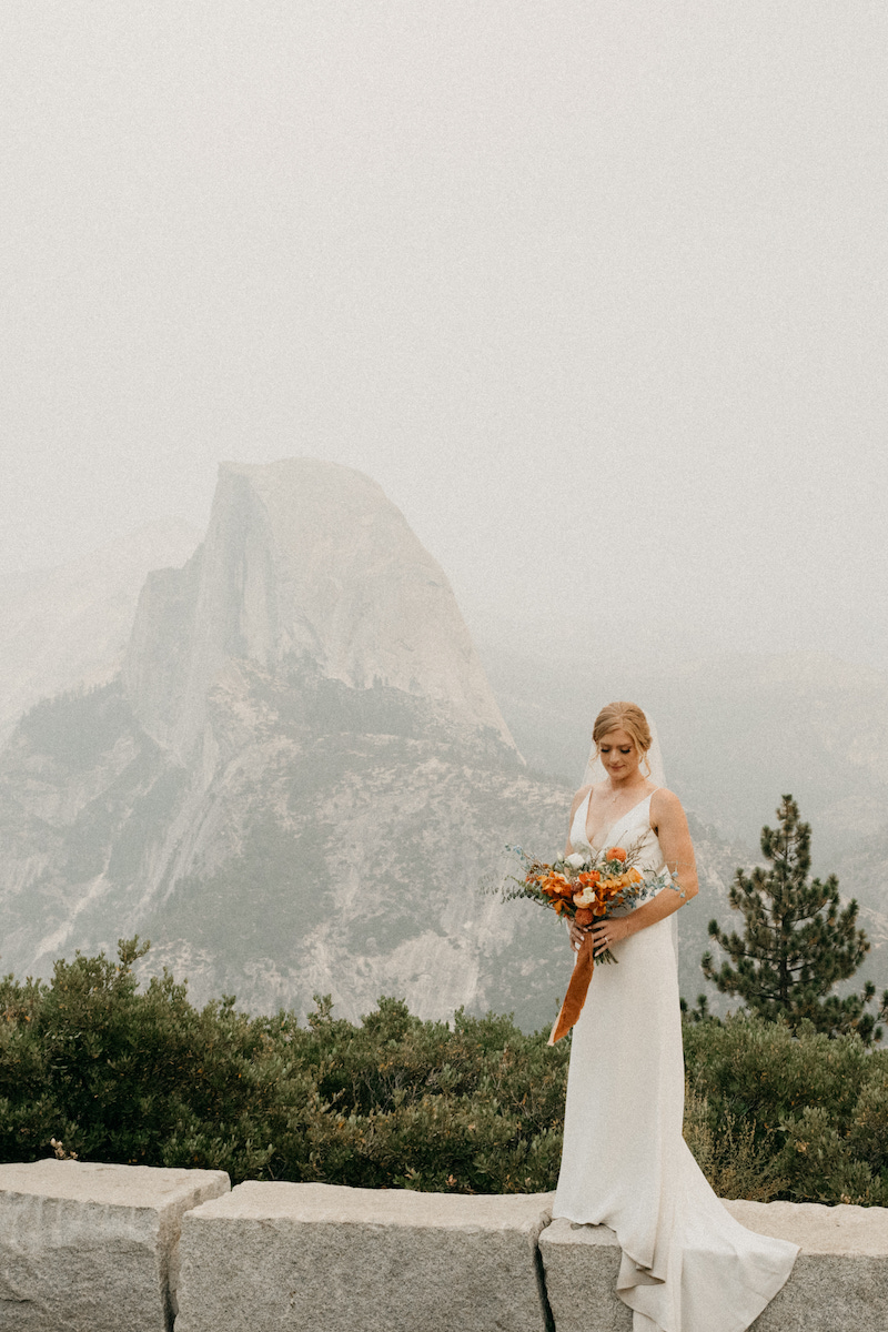 Bride standing with bouquet with Yosemite's Half Dome in the distance