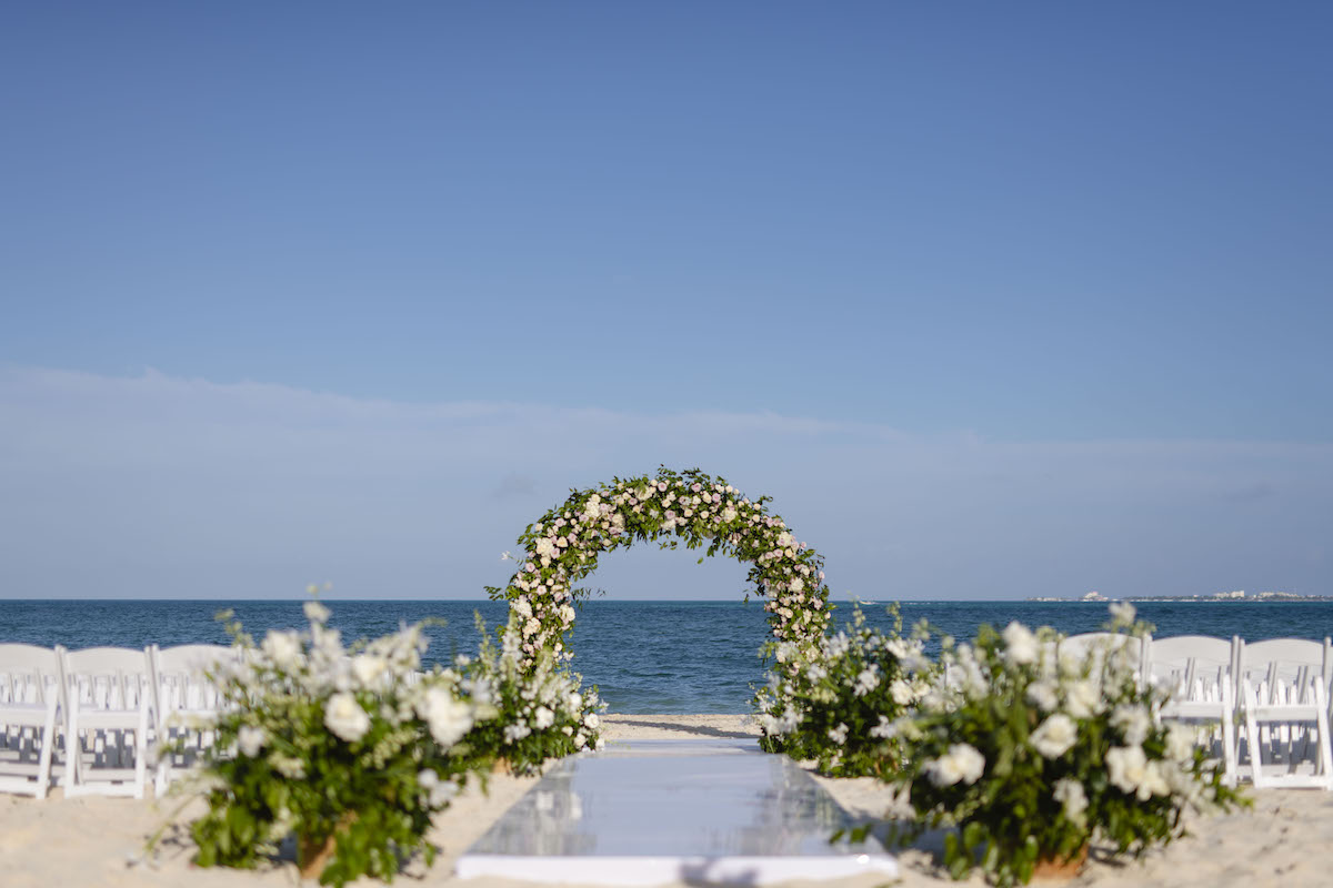 Wedding arch on beach surrounded by chairs