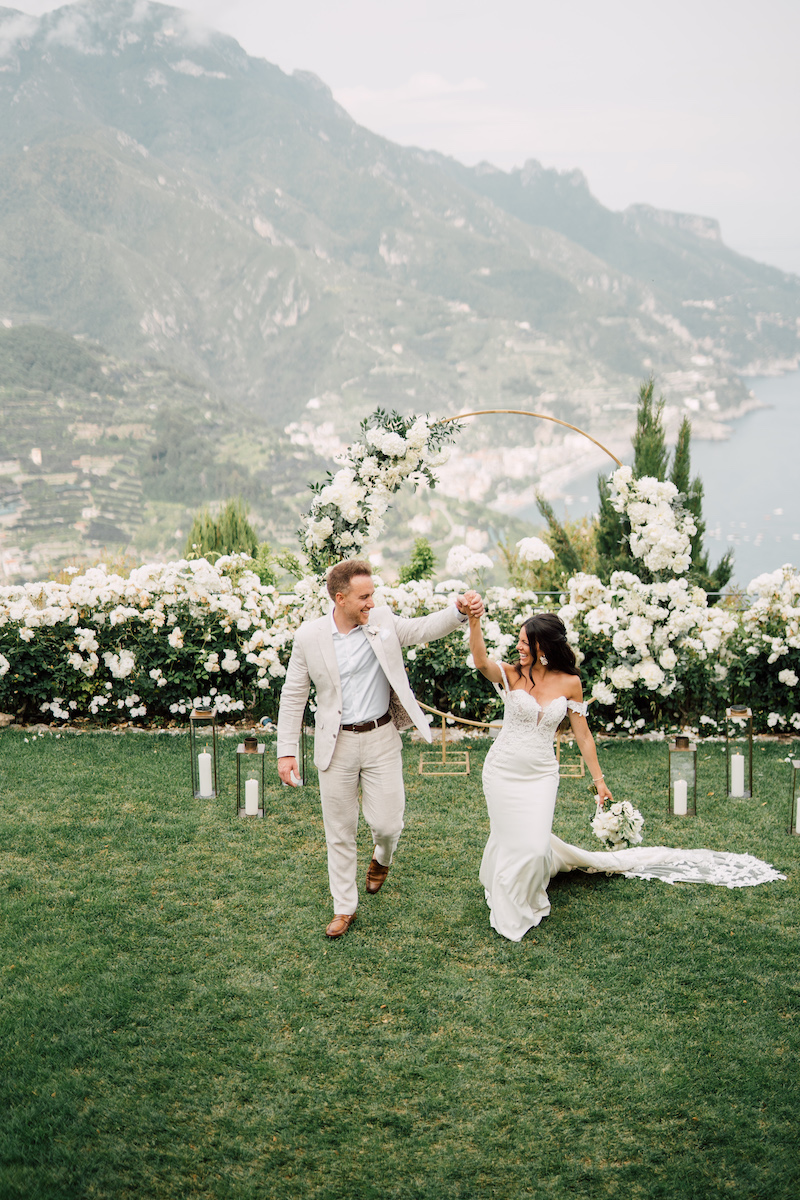 Bride and groom among white flowers at a ceremony on a cliffside