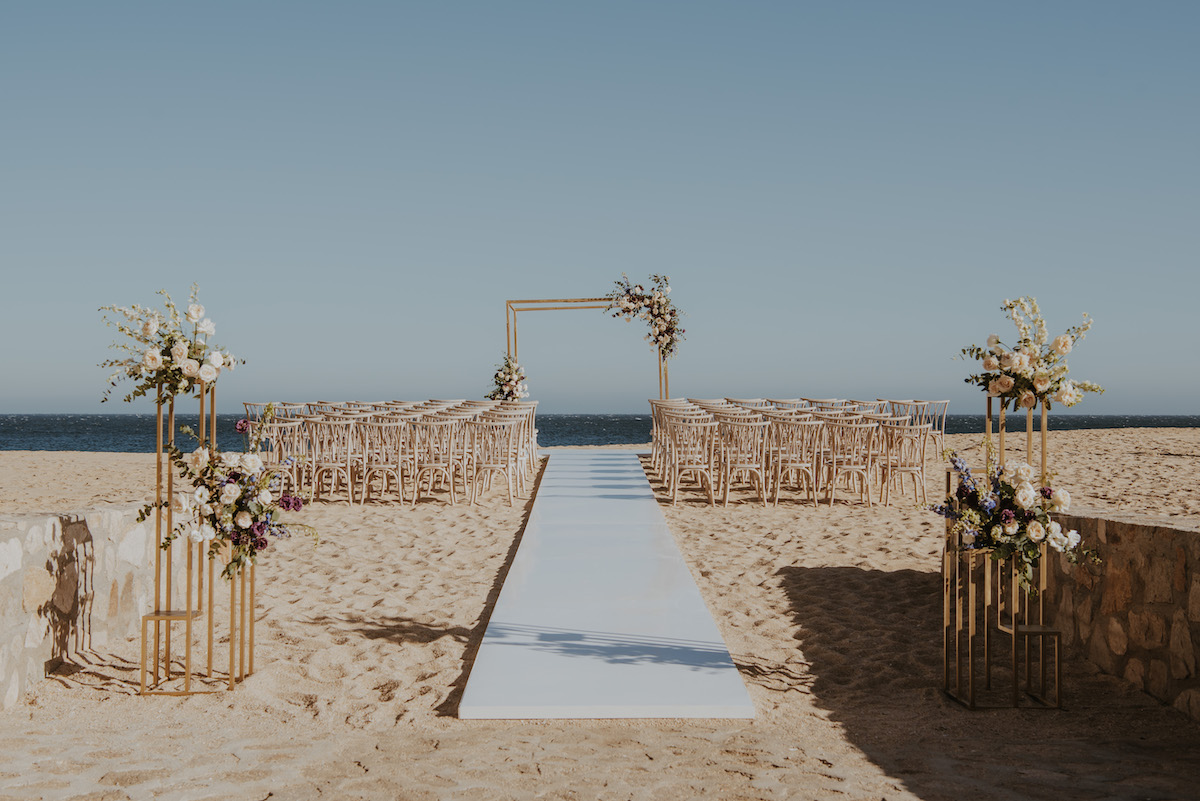 Empty wedding ceremony set up of an aisle, chairs and wedding arch.