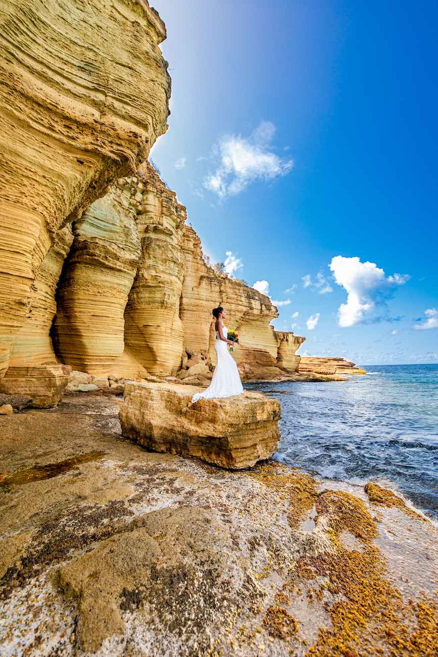 Bride posing near cliffs in the Caribbean.