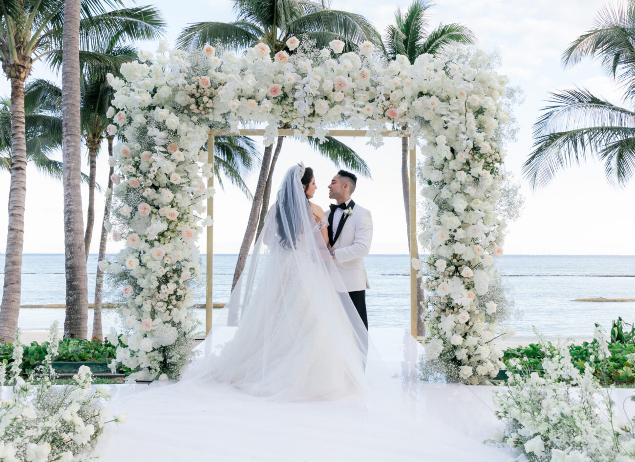 Wedding couple standing under arch in ceremony on the beach