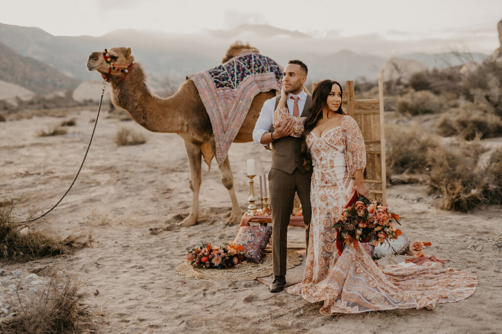 Wedding couple posed in front of camel in Moroccan style Elopement