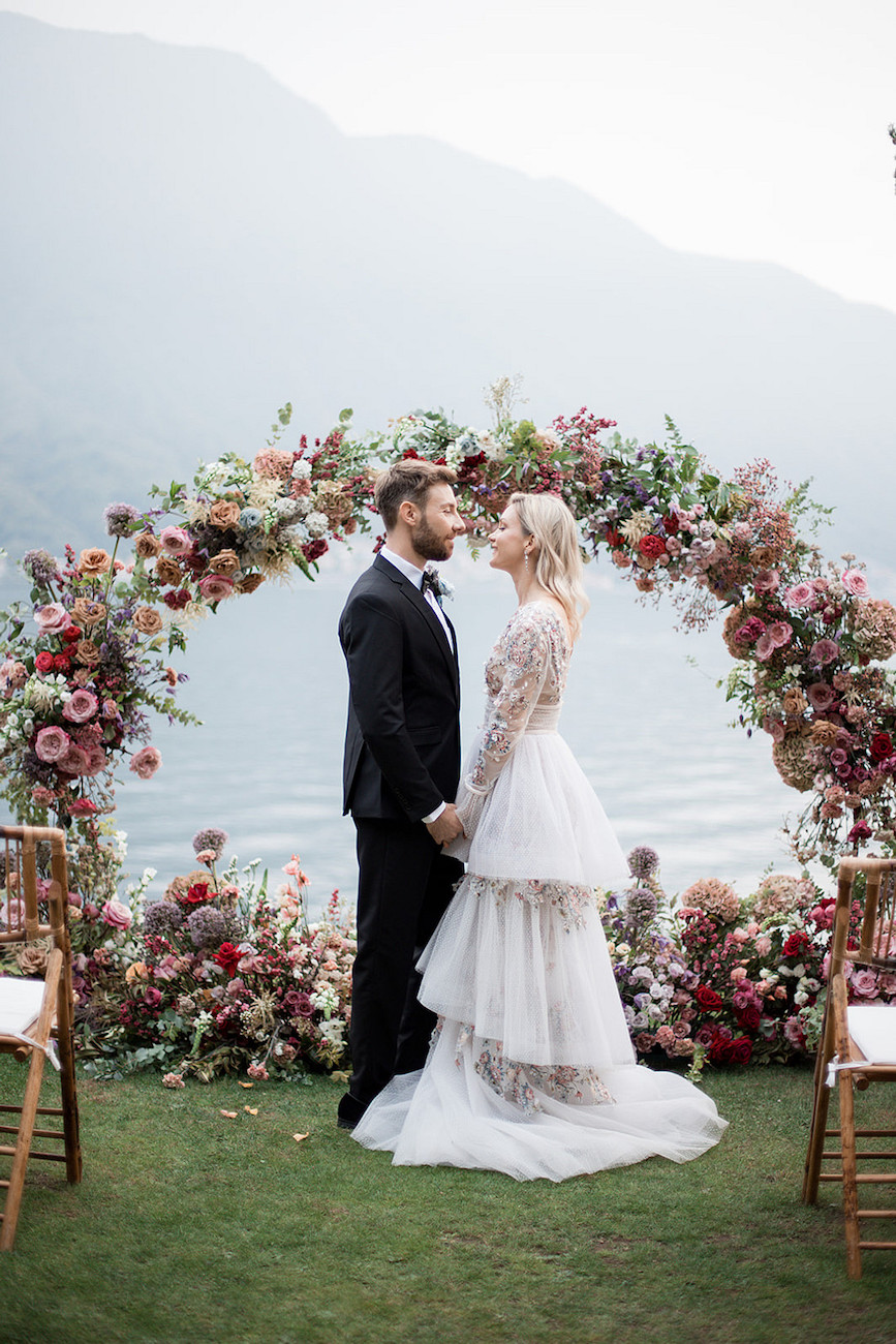 Bride and groom about to kiss under bright floral wedding arch