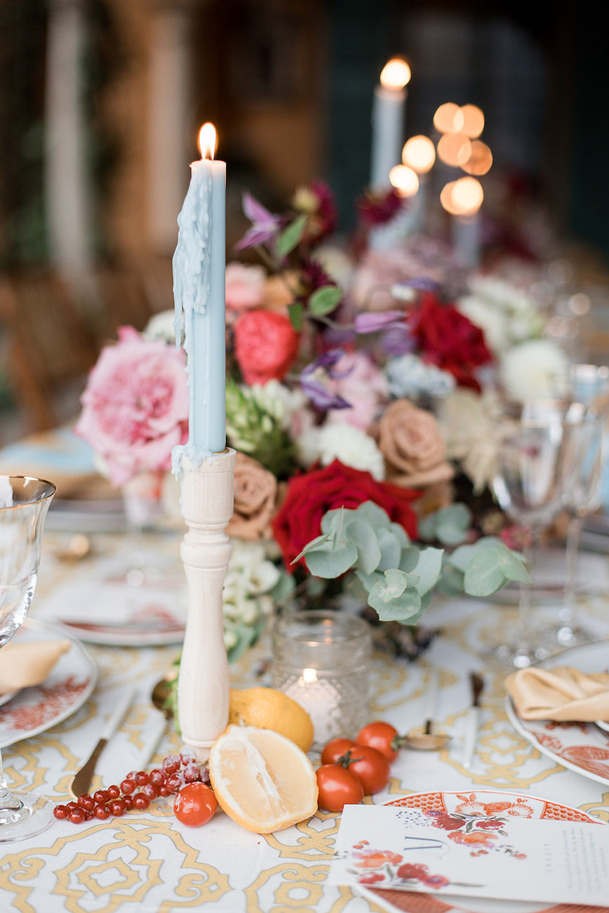 Light Blue tapered candle next to floral centerpiece 