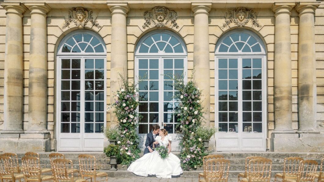 Wedding couple sit at altar in front of Chateau de Champlatreux