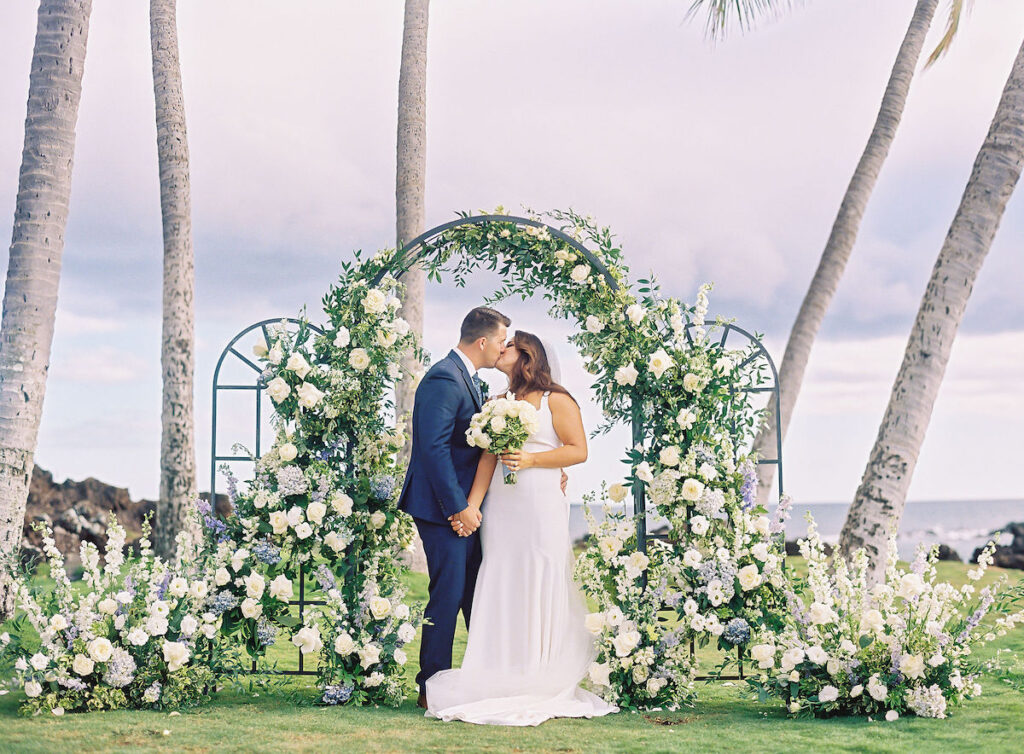 bride and groom under floral arch