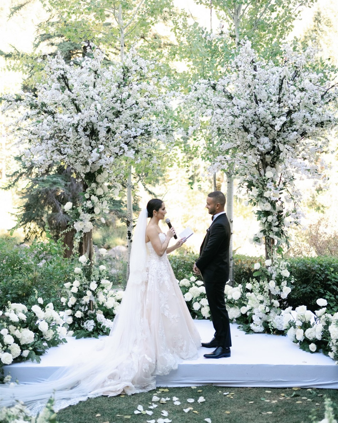 couple at ceremony framed by two white floral trees