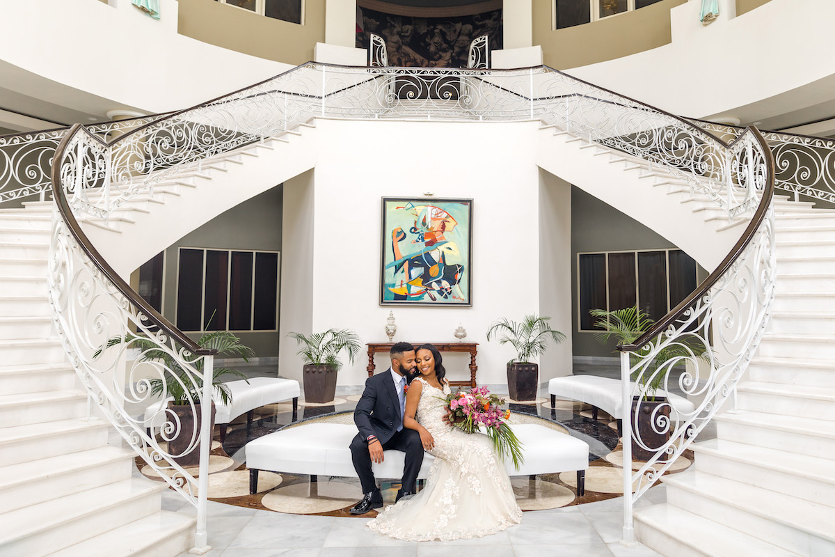 bride and groom sit framed by two staircases