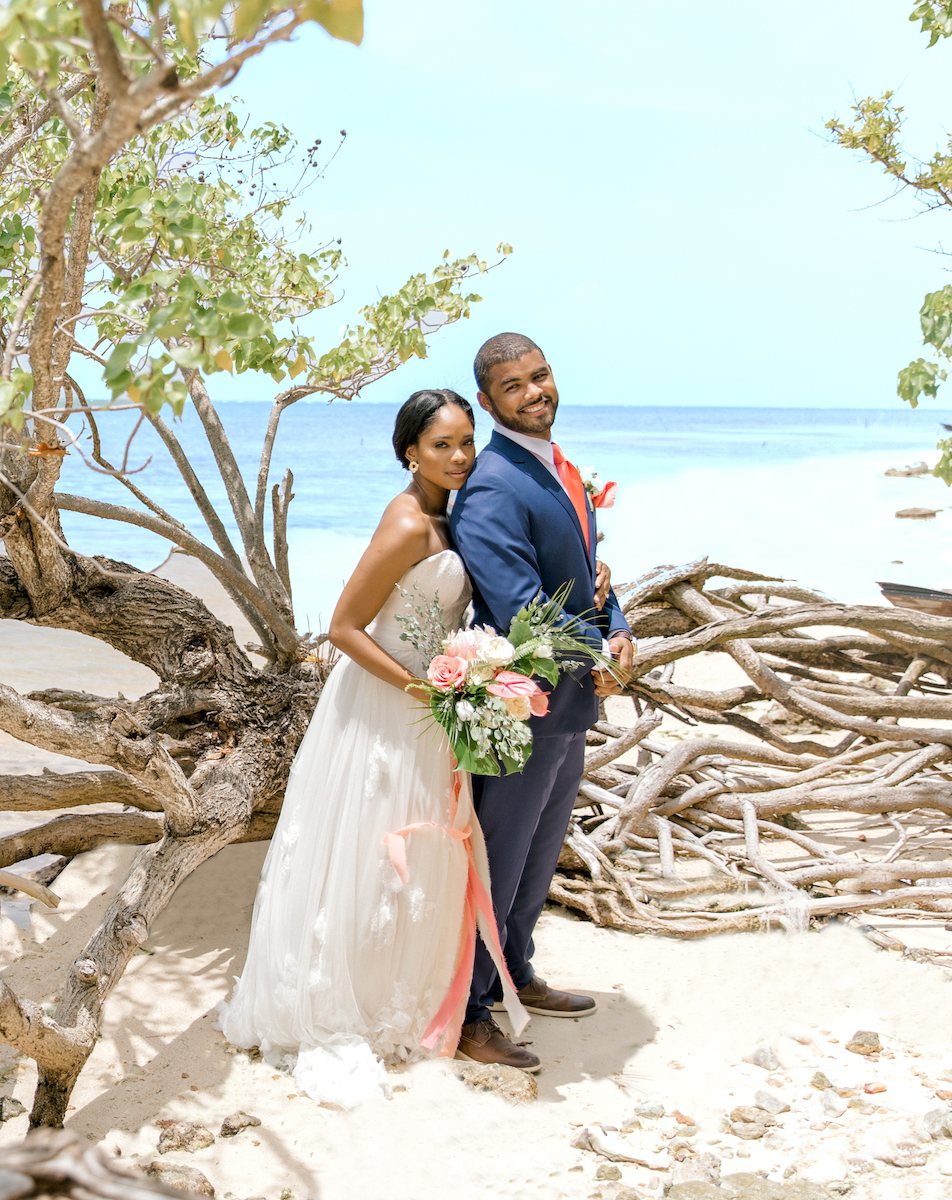bride and groom on beach with driftwood
