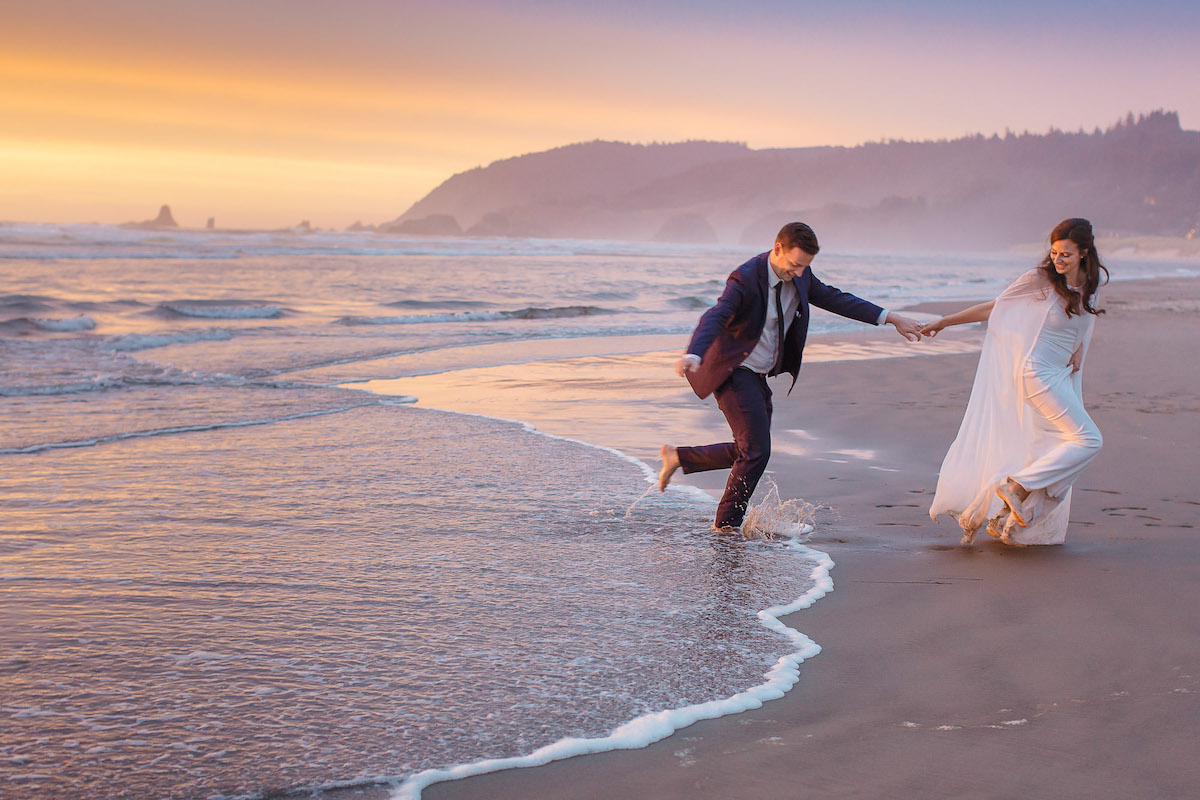 Wedding couple run after each other on beach with sunset