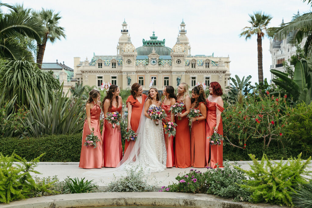 bride in front of St. Charles Church in Monaco with bridesmaids in salmon dresses