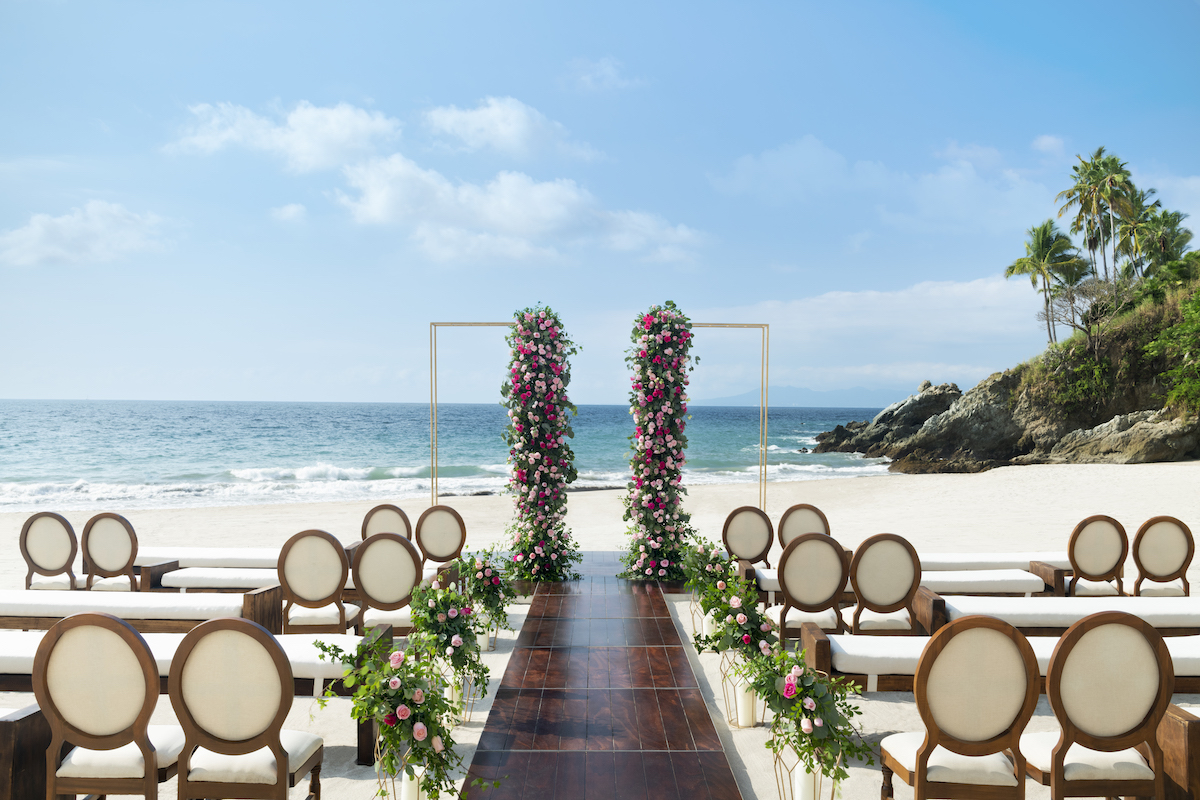 Hyatt Ziva Puerto Vallarta Pureza Beach wedding ceremony setup with wooden aisle and gold arch with pink florals