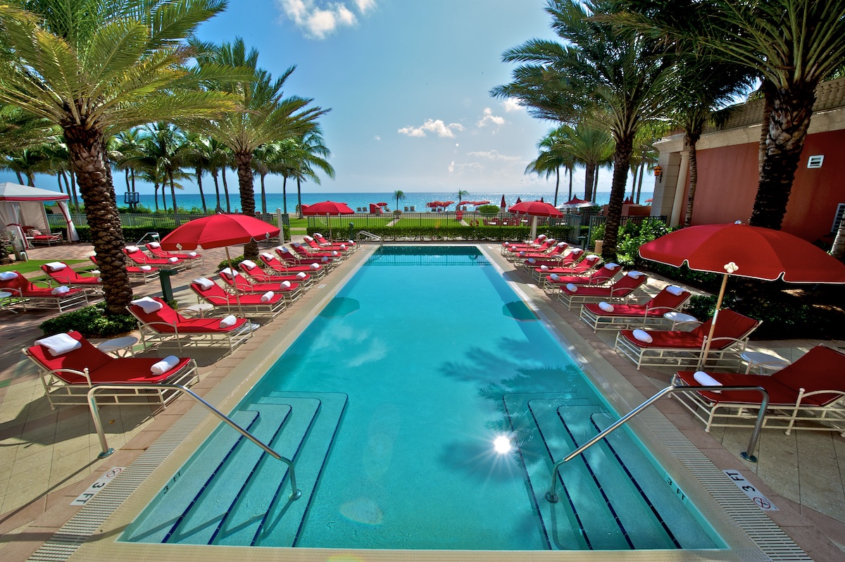 rectangular pool with red lounge chairs
