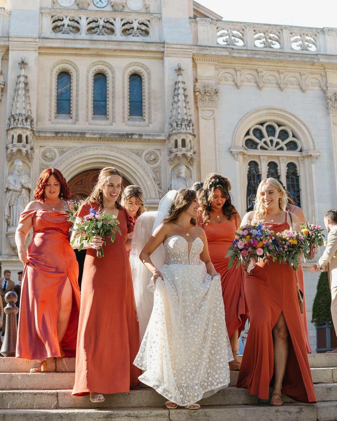 bride in strapless gown laughing with bridesmaids in silk and chiffon salmon dresses