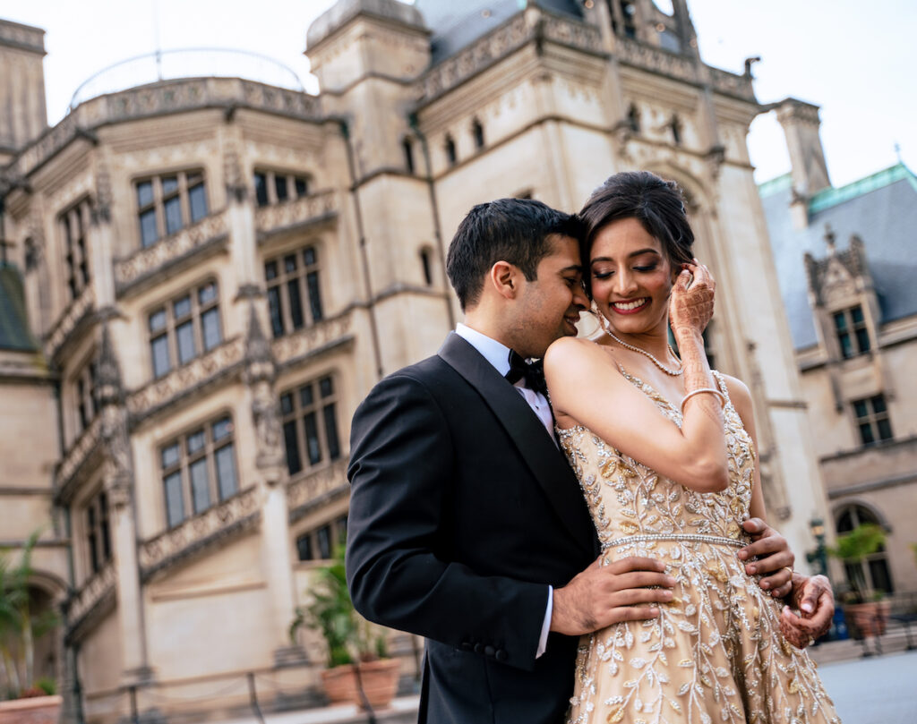 Indian bride and groom embrace in front of Biltmore Estate