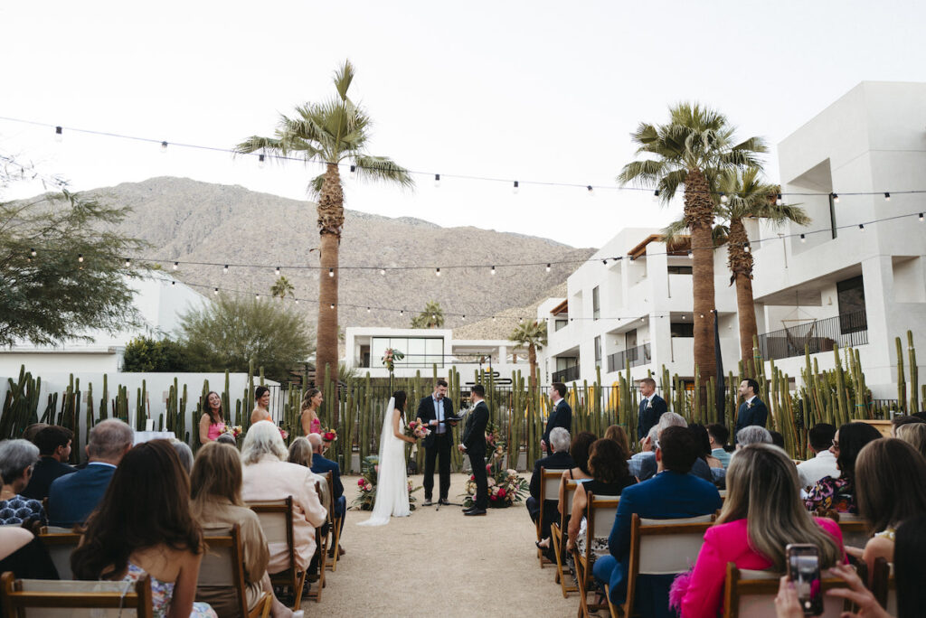 Lil and Michael stand at altar in center of Drift hotel with Palm Springs mountain behind