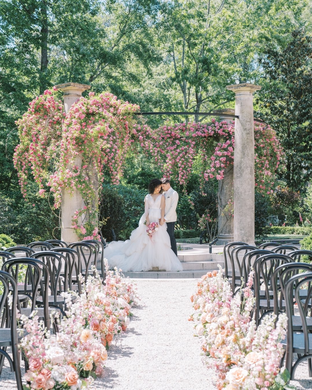 Bride and groom embracing at altar among light pink roses