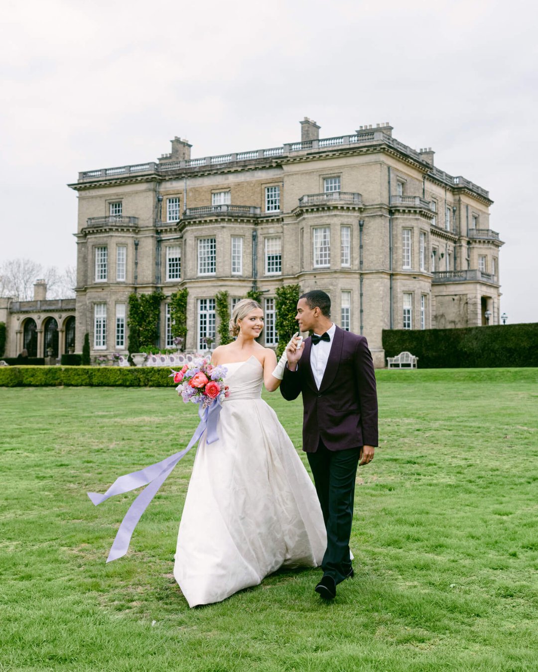 Wedding couple posing in front of Hedsor House in England.
