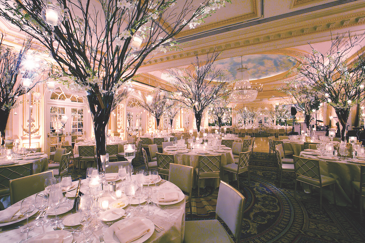 Elegant banquet hall with cherry blossom centerpieces, crystal chandeliers, and set tables ready for an event.