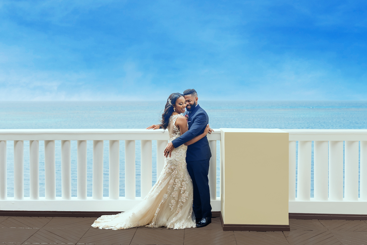 bride and groom hug on terrace overlooking the Caribbean Sea