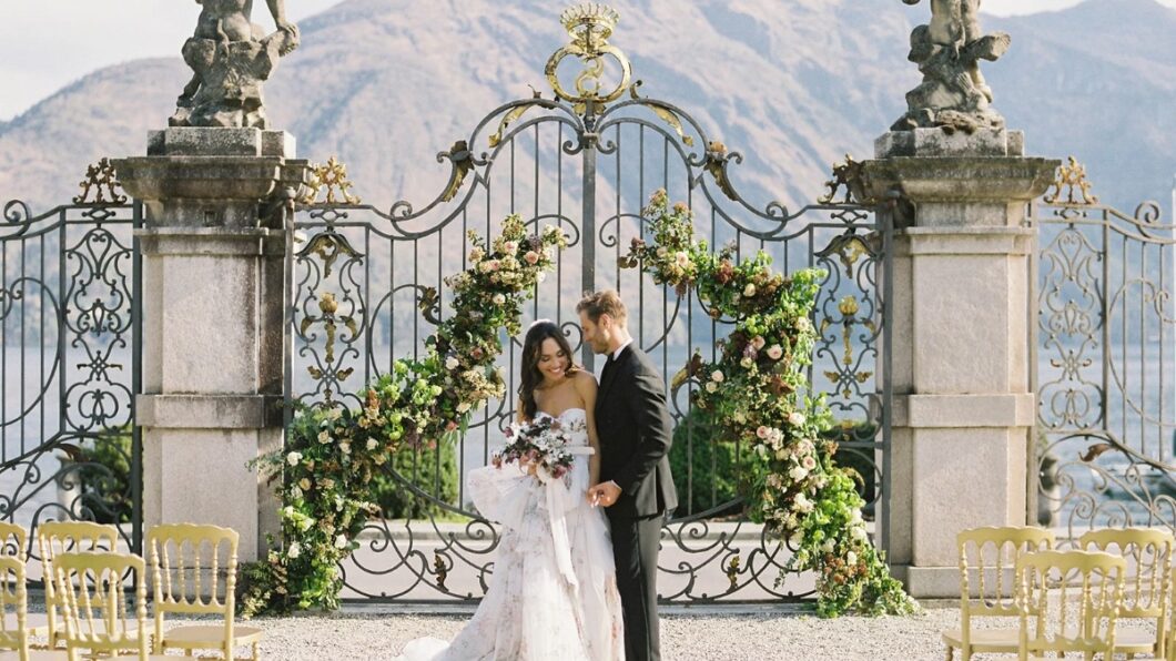 A bride and groom in front of wrought iron gates in lake Como