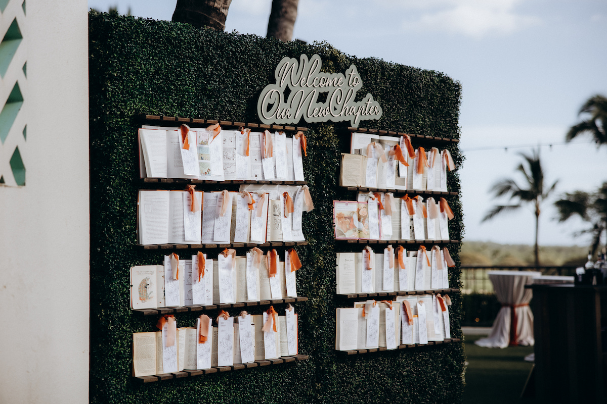 "welcome to our new chapter" sign with wall of children's books as the table escort cards