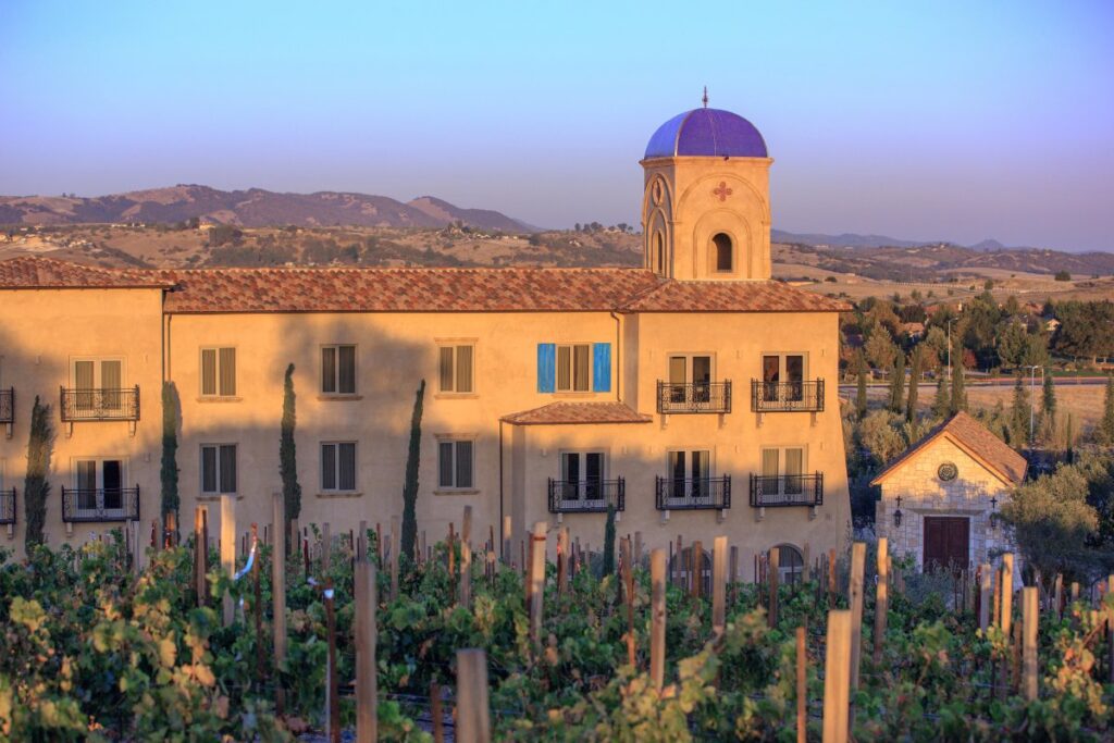 Tuscan-style building at sunset surrounded by rolling hills and vineyards