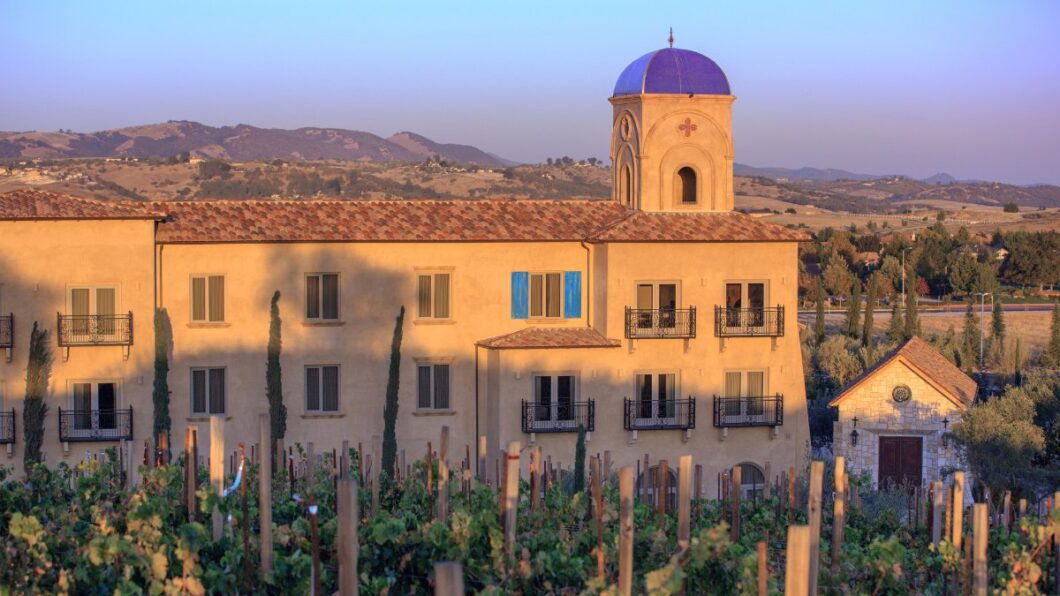 Tuscan-style building at sunset surrounded by rolling hills and vineyards