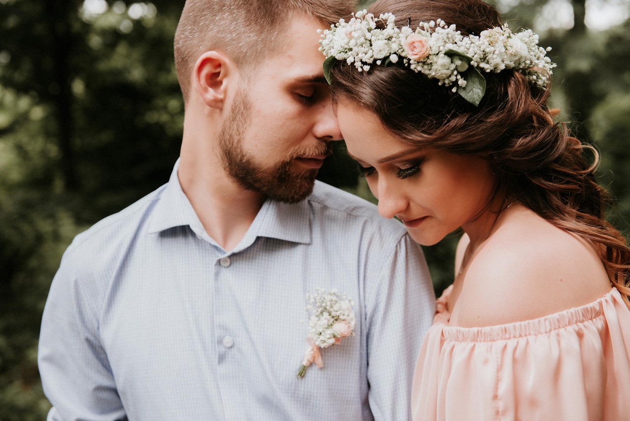 groom in blue button down and bride with baby's breath floral crown and off the shoulder pink dress