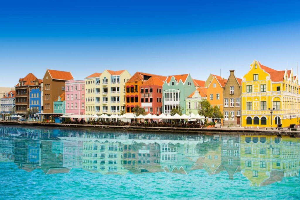 Colorful colonial buildings with gabled roofs flank a harbor in Willemstad, the capital city of Curaçao.