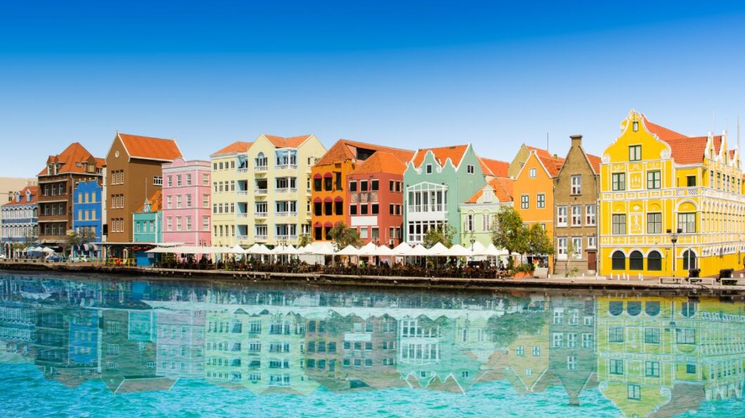 Colorful colonial buildings with gabled roofs flank a harbor in Willemstad, the capital city of Curaçao.