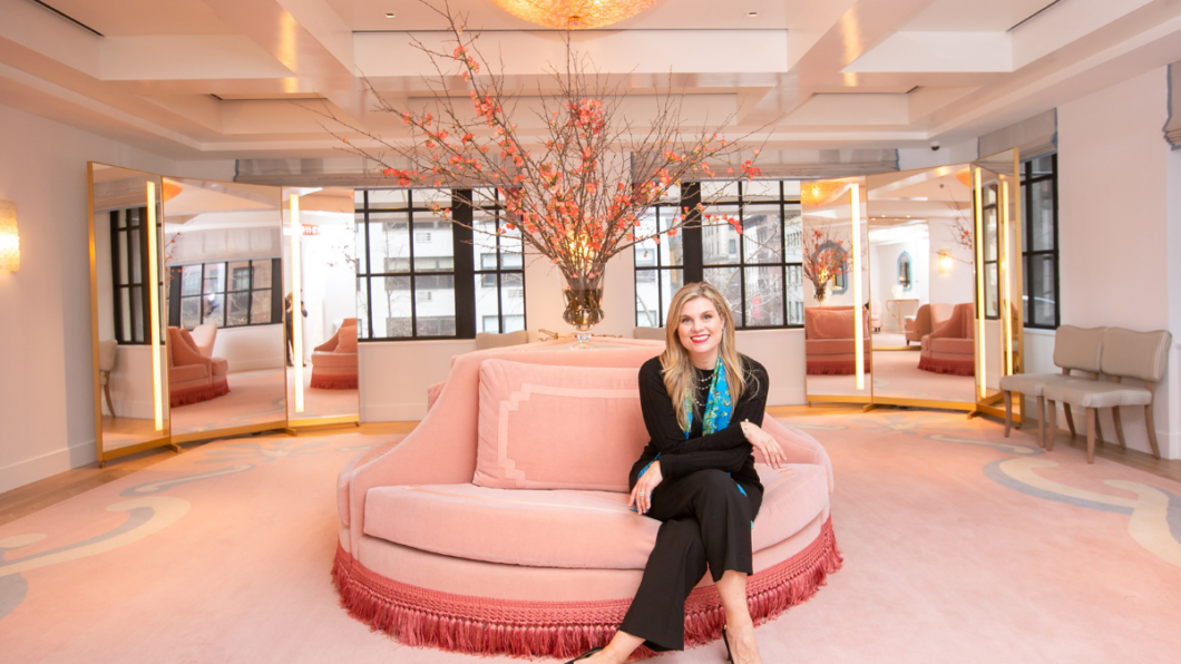 woman sitting on pink round couch in stylish bridal dress room