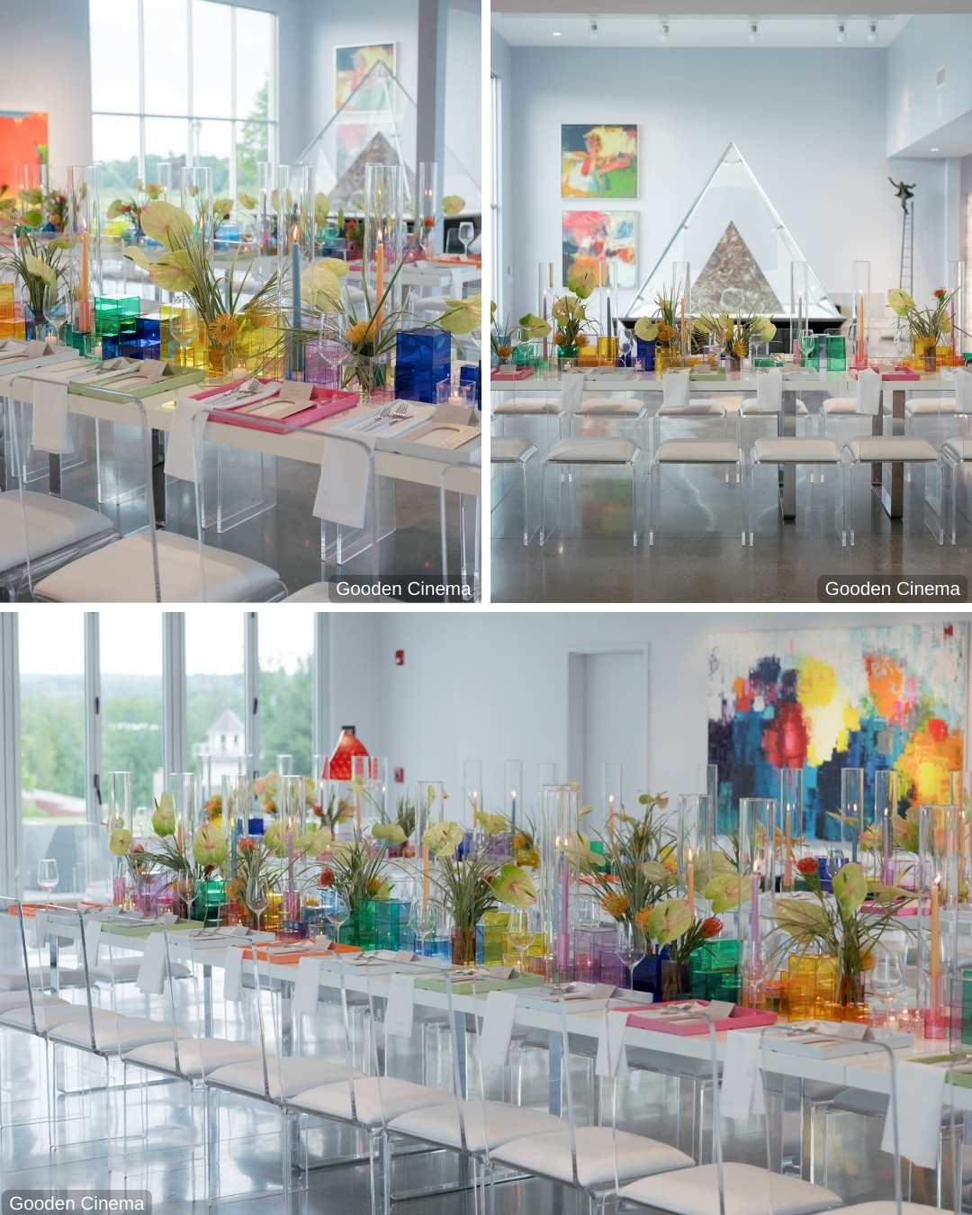 A modern event space with clear acrylic chairs and tables decorated with colorful glass vases, flowers, and tall candles. Artworks and large windows surround the room, and there are white napkins on each chair. Bright, abstract paintings adorn the walls.