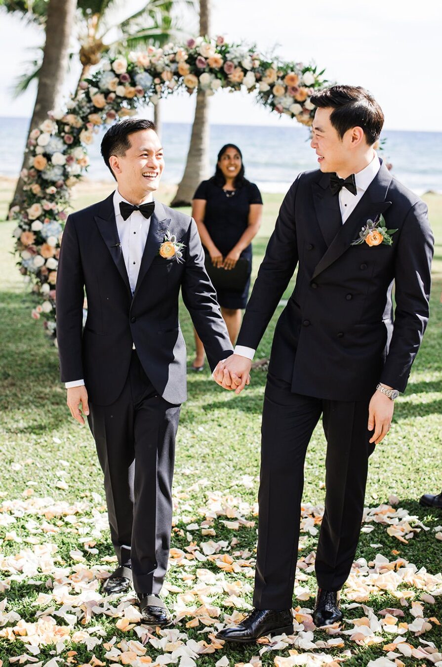 grooms smile at each other walking back up the wedding aisle
