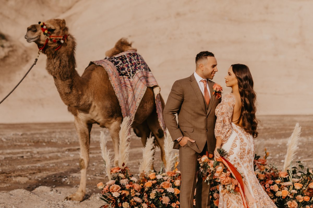 bride and groom pose in front of camel