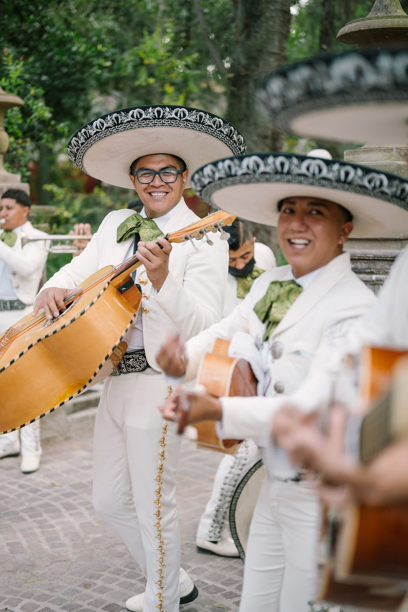 Mariachi band members smile at camera holding instruments