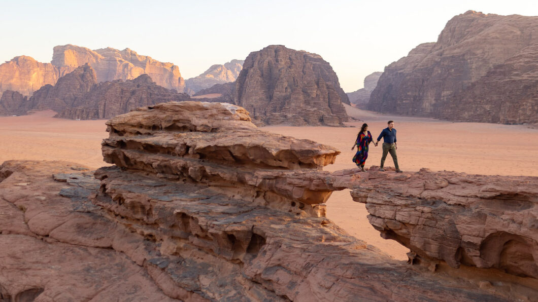 bride and groom walk over little bridge in wadi rum in jordan