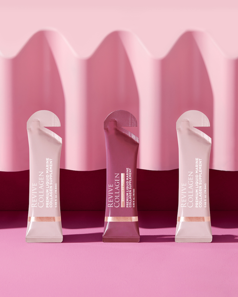 Three sachets of Revive Collagen on a pink surface with a wavy pink background. The middle sachet is a darker shade than the two on either side.