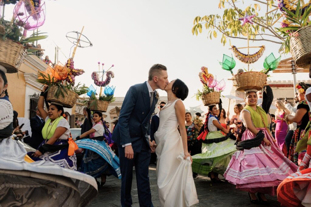 couple kissing as women in Mexican dresses twirl around them